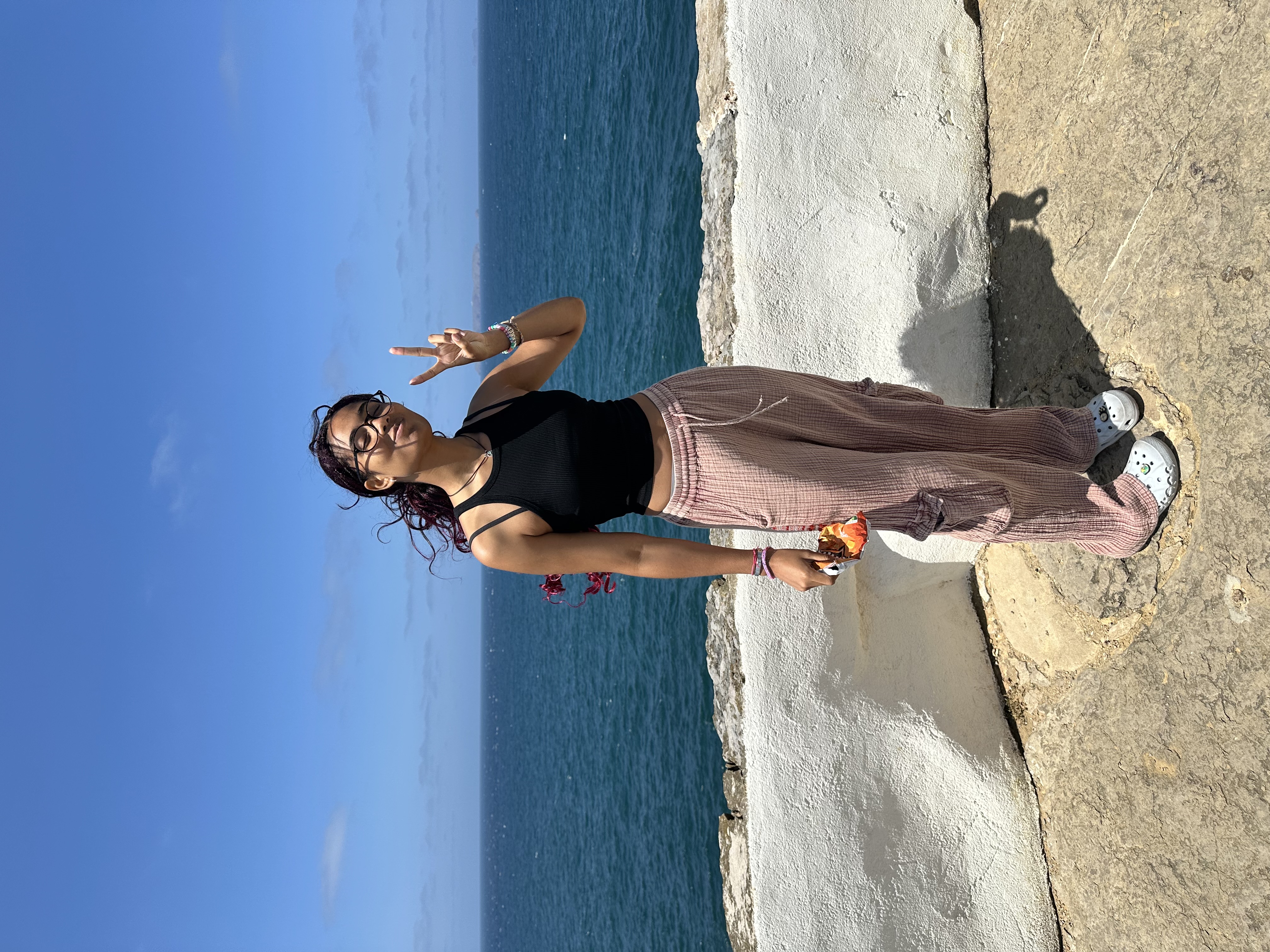 Anais by the ocean, peace sign up, sun on her face